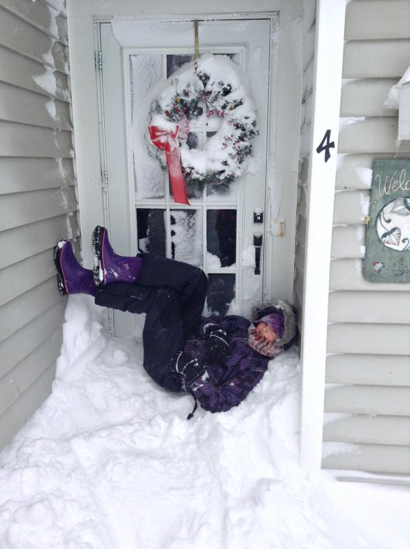 Hannah Watt reclines on a pile of snow in her doorway in Mattapoisett. BY CHRISTINE WATT